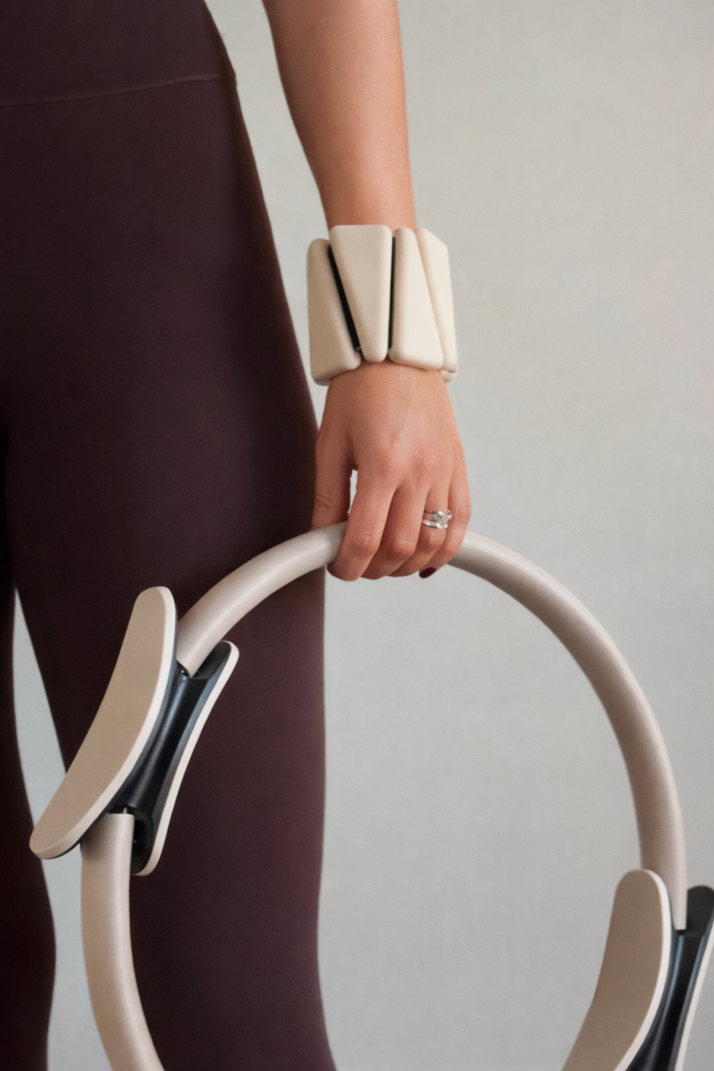 A member holding a Pilates ring while wearing wrist weights