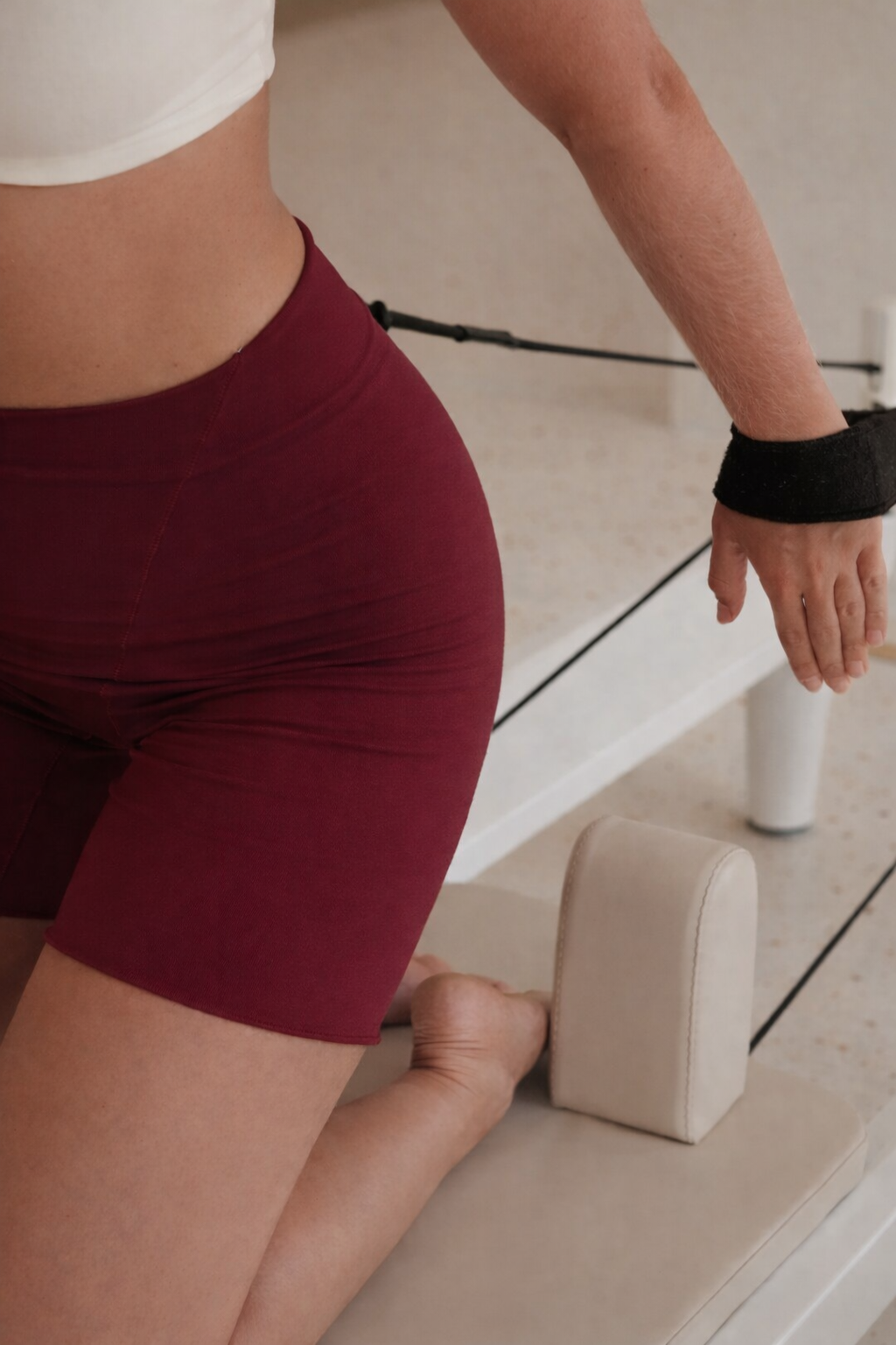 A member kneeling on the reformer in burgundy Solhaus shorts